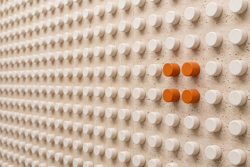 A travertine wall of ceramic knobs with four orange knobs singled out